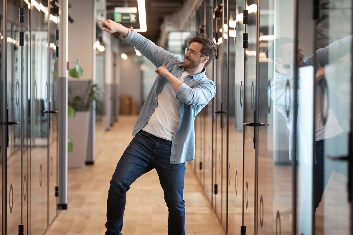 Energetic man celebrating success in a modern office hallway.