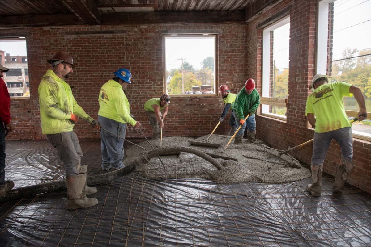 Construction crew pouring concrete inside a mill building restoration in the Pioneer Valley, representing strong foundations and structure for a WordPress website for home services
