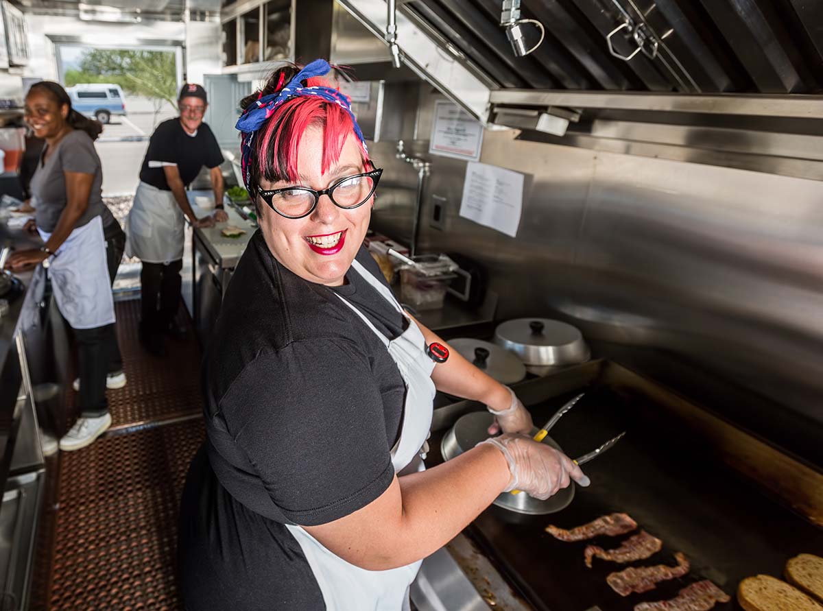 Happy restaurant employee working in a small business kitchen with a strong company culture