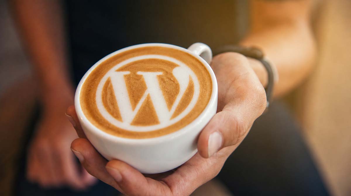 Cup of coffee with the WordPress logo created in the foam.